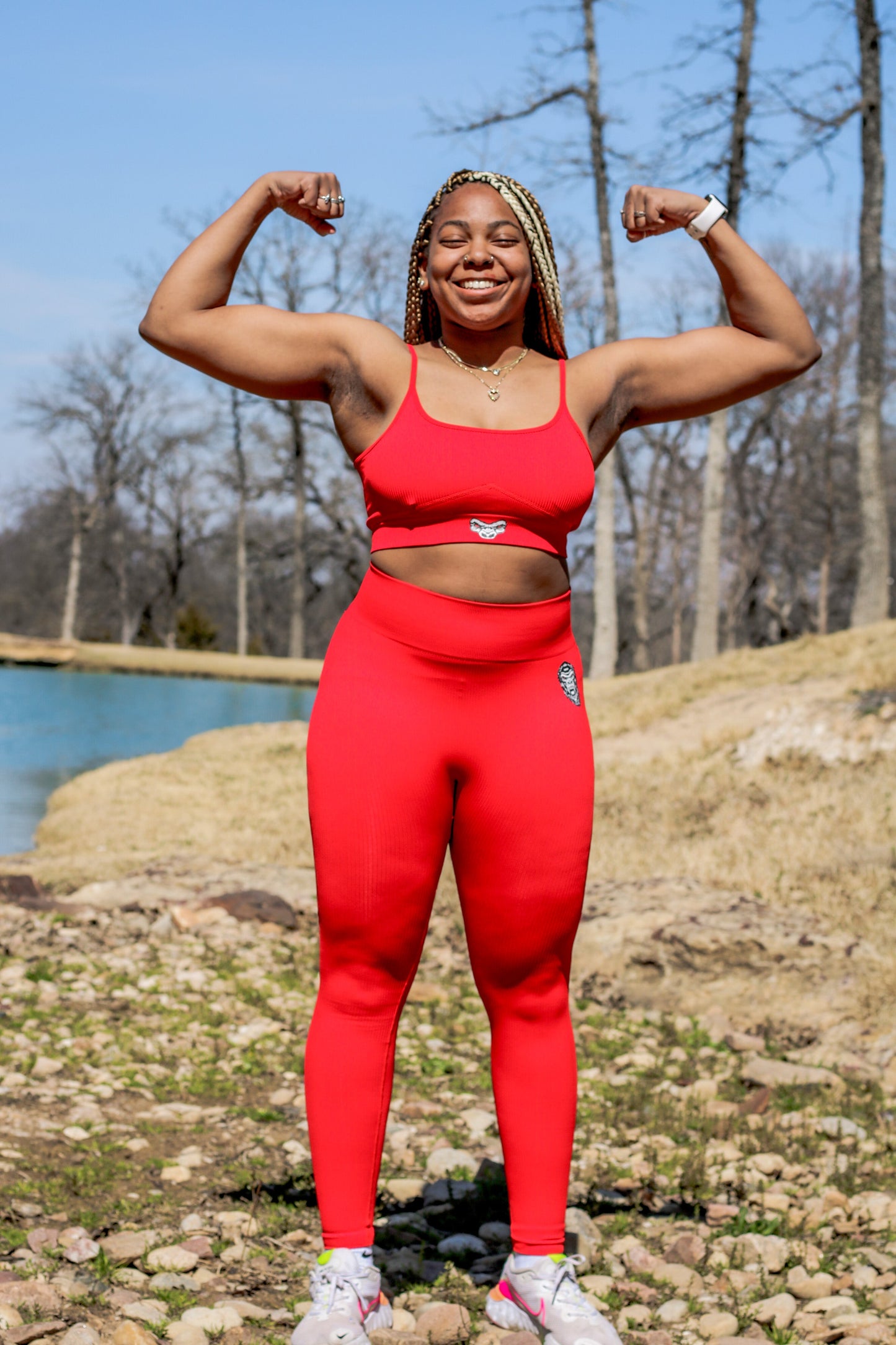 woman flexing with red spaghetti strap Last Rep sports bra and leggings