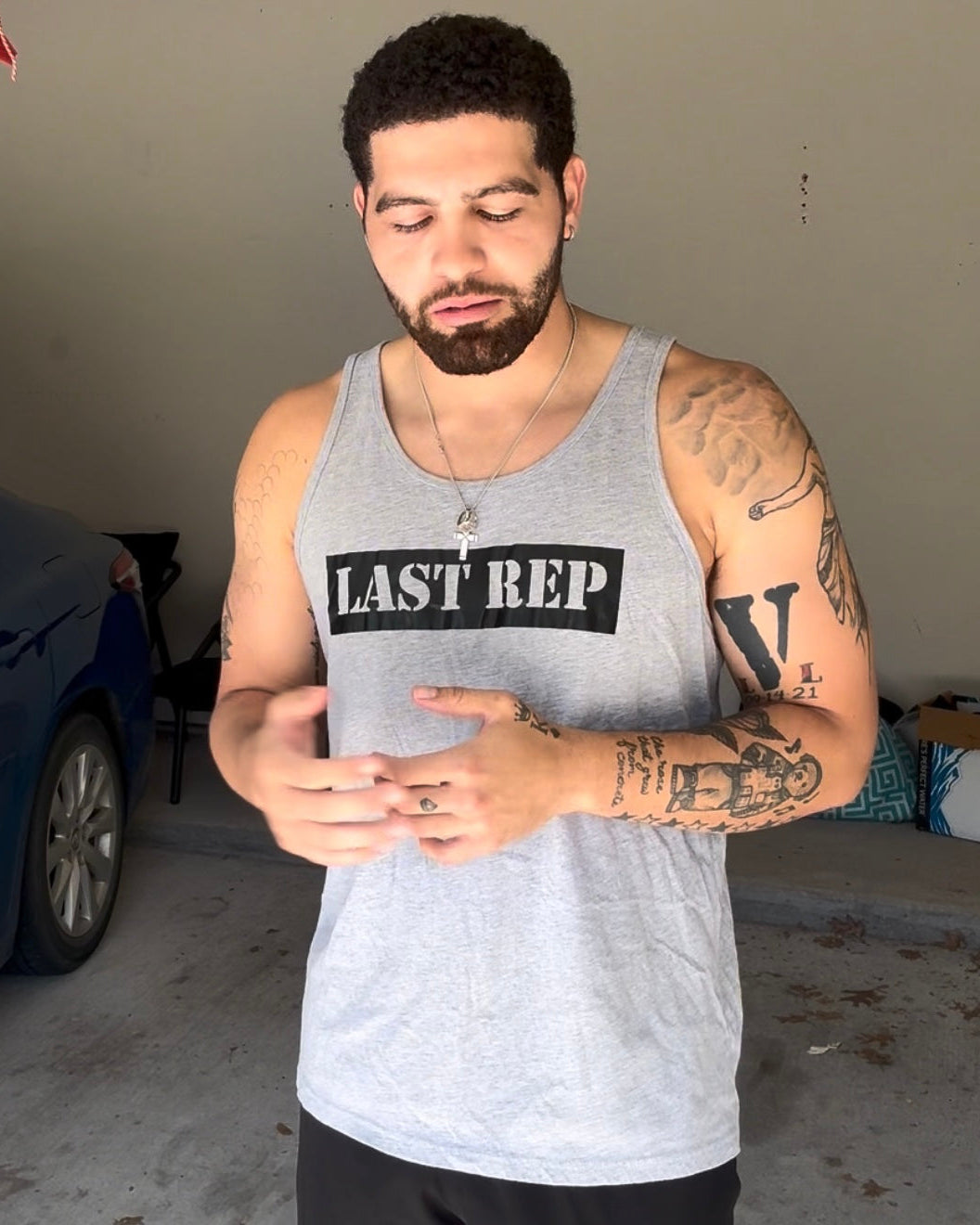 Man wearing a 'Last Rep' tank top in a garage.