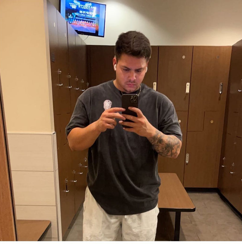 Man taking a mirror selfie in a locker room wearing black Last Rep pump cover