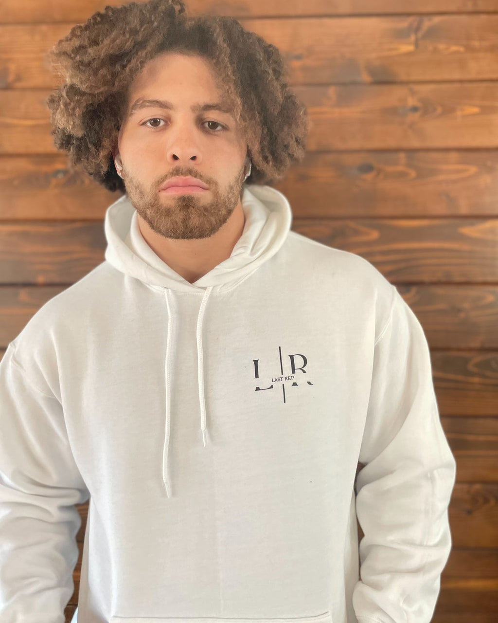 Person wearing a white hoodie with a logo against a wooden background
