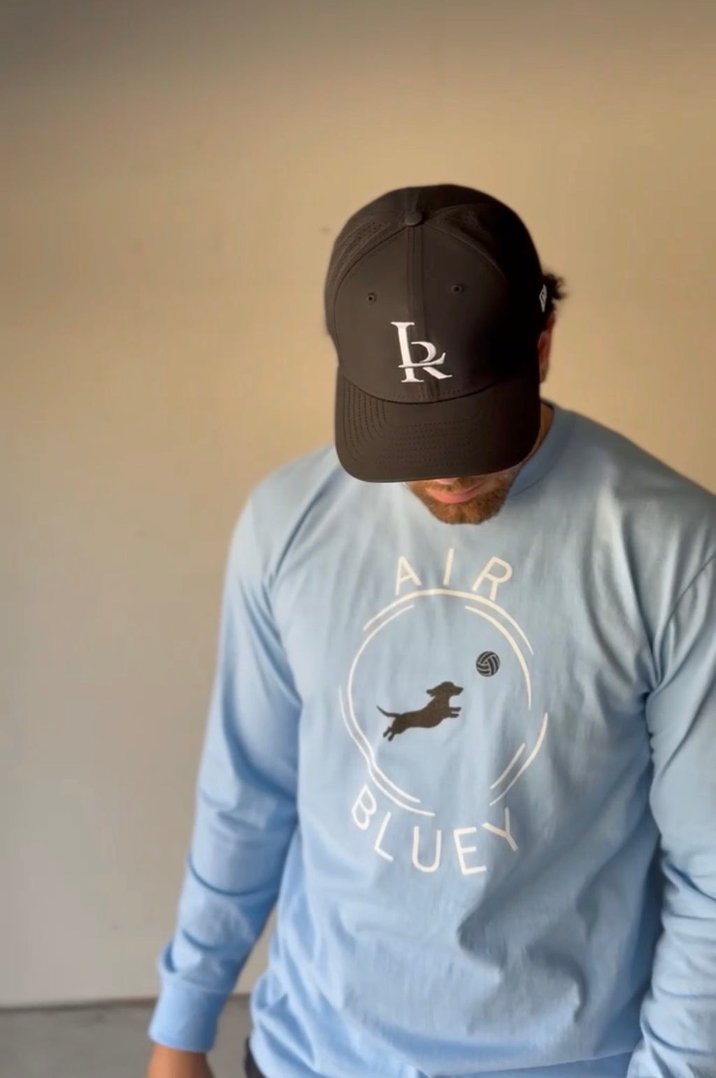 Person wearing a black cap and light blue sweatshirt with branding