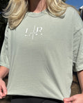 Person wearing a green t-shirt with a logo on it, standing outdoors.