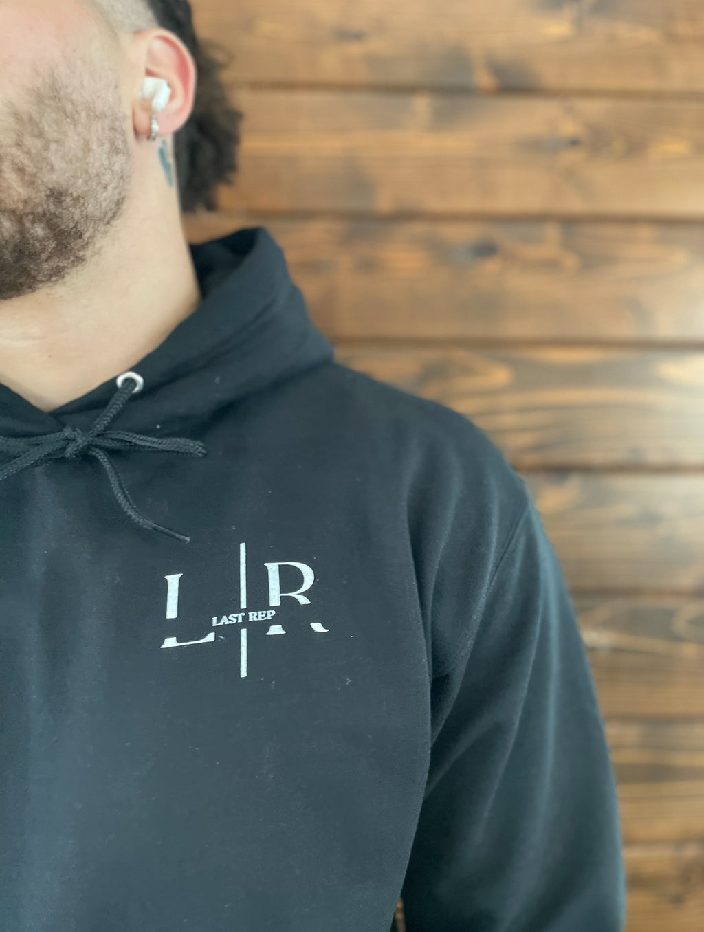 A person wearing a black hoodie with the Last Rep logo on the front.