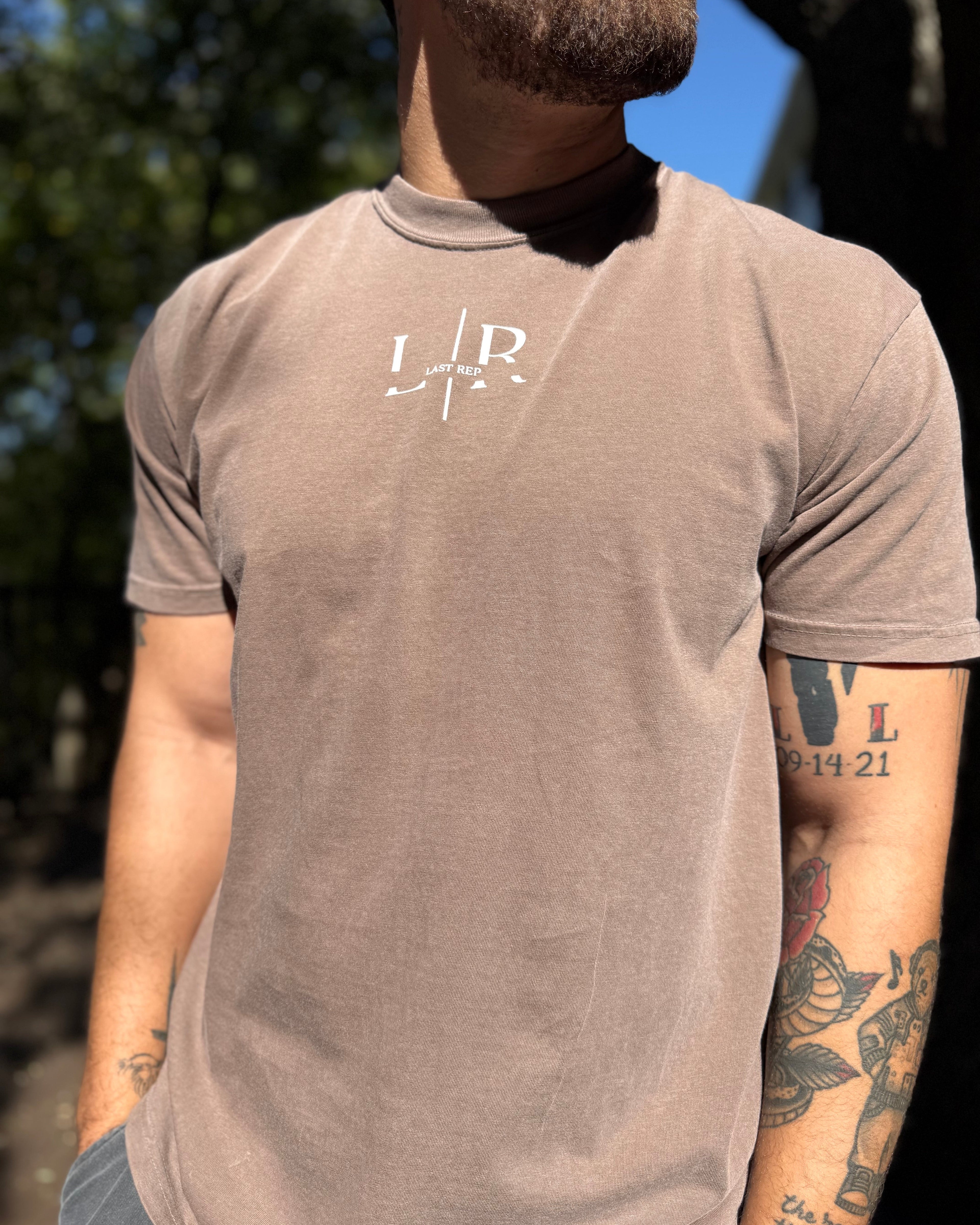 Man wearing a brown t-shirt with a logo outdoors