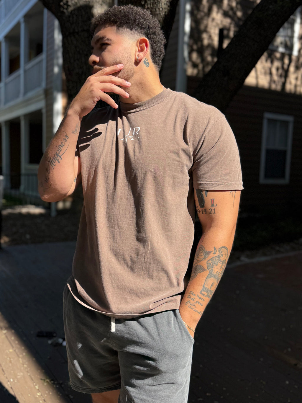 Man in casual clothing standing outdoors under a tree