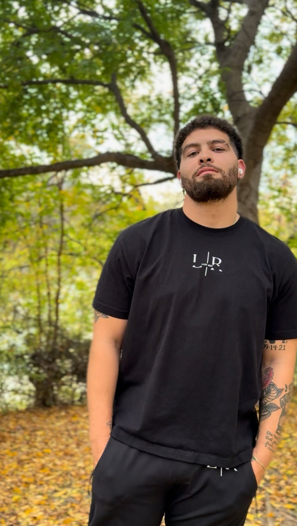 Man wearing a black t-shirt with a last rep logo in a forest setting