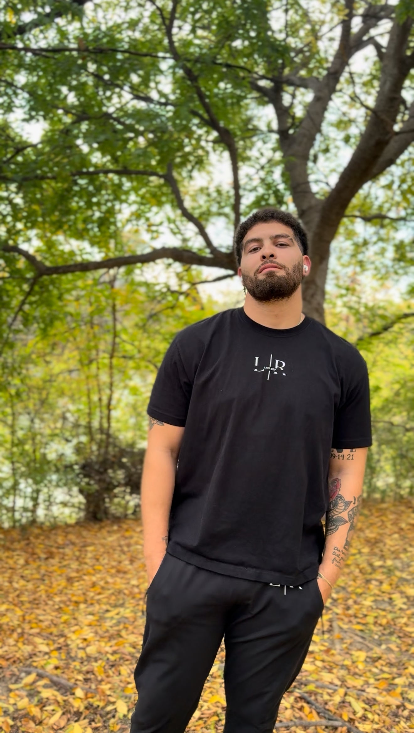 Man wearing a black t-shirt with a last rep logo in a forest setting