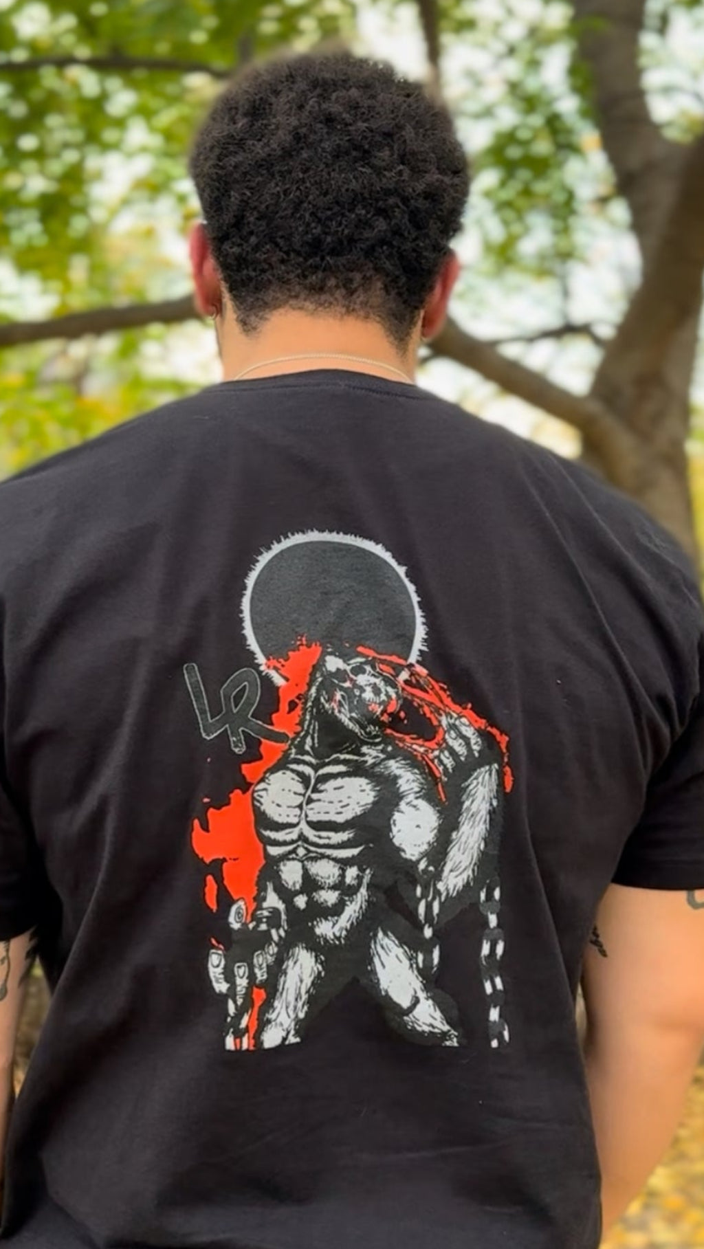 Person wearing a black t-shirt with a graphic design outdoors