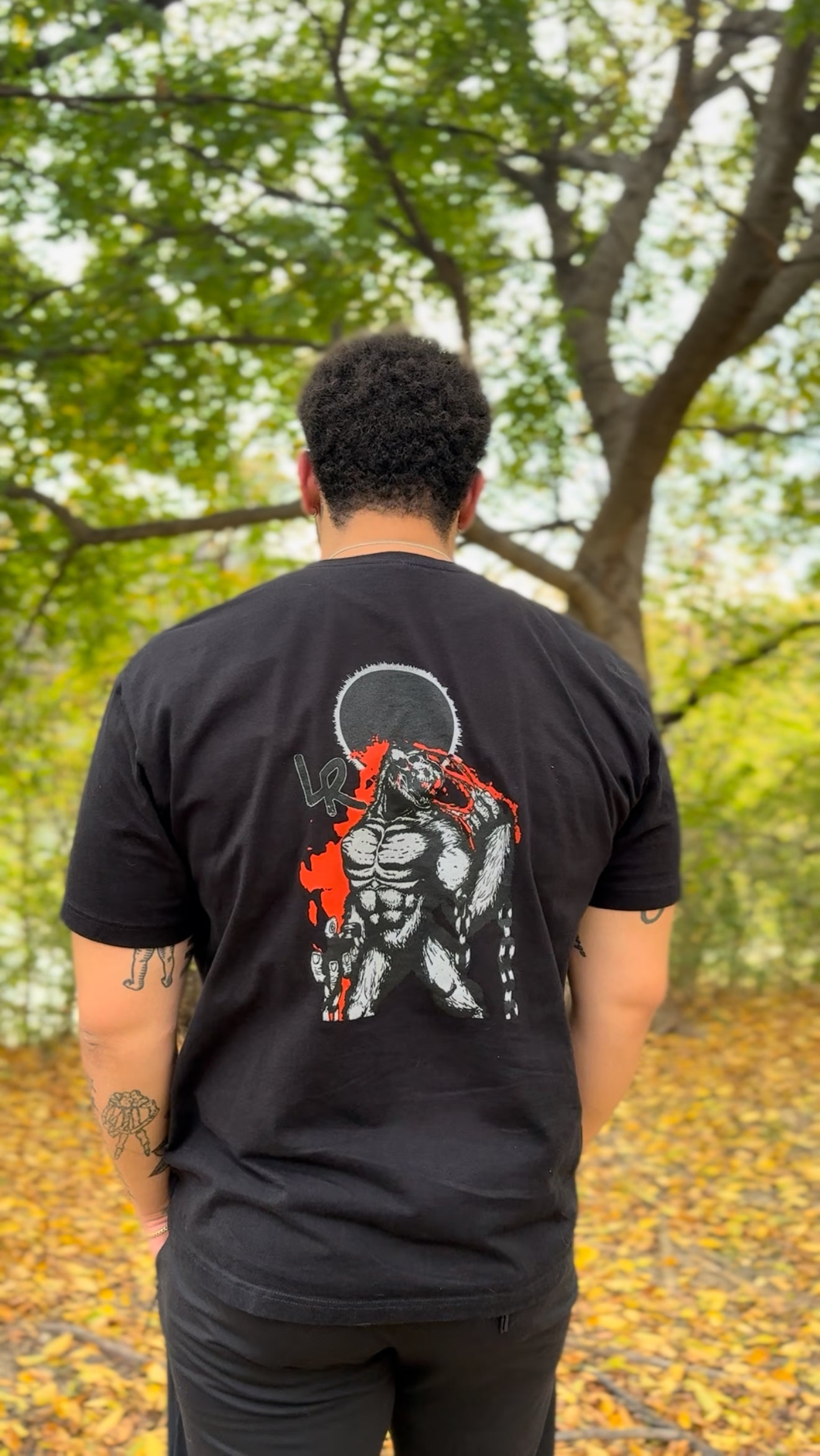 Person wearing a black t-shirt with a graphic design outdoors