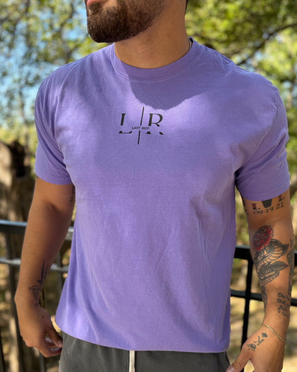 Person wearing a purple t-shirt with a logo outdoors