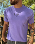 Person wearing a purple t-shirt with a logo outdoors