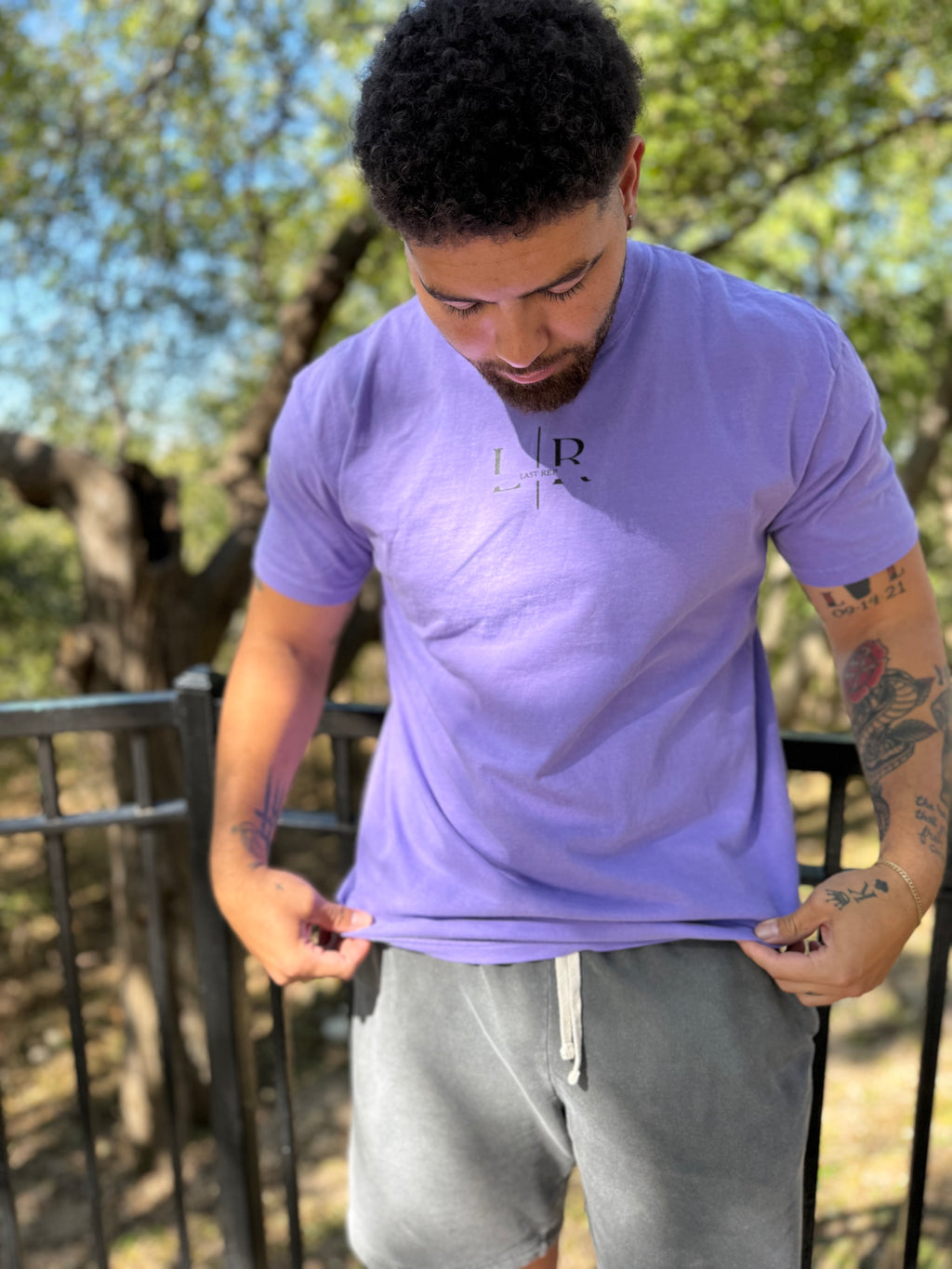 Man wearing a purple t-shirt with  last replogo outdoors