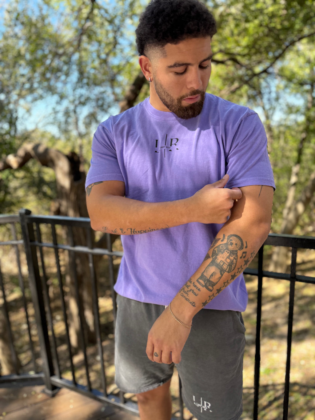 Man wearing a purple t-shirt with a logo outdoors