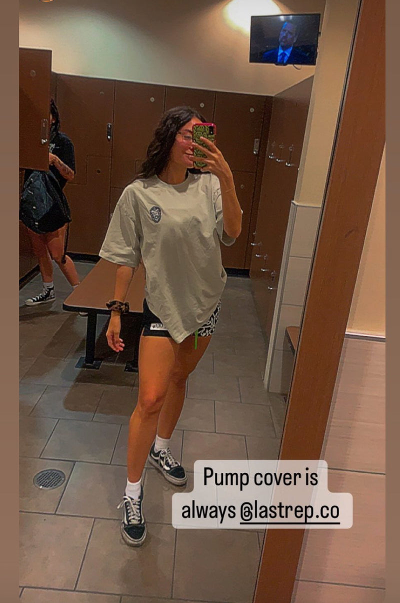 Person taking a mirror selfie in a locker room with Last Rep pump cover on.