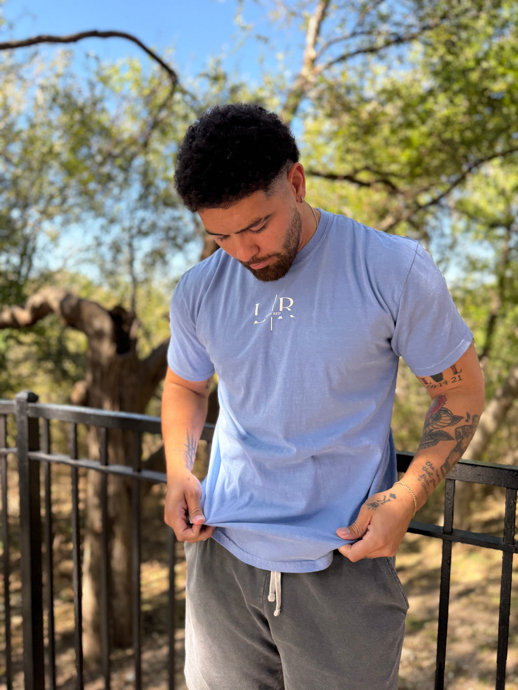 Man wearing a light blue t-shirt with a logo outdoors