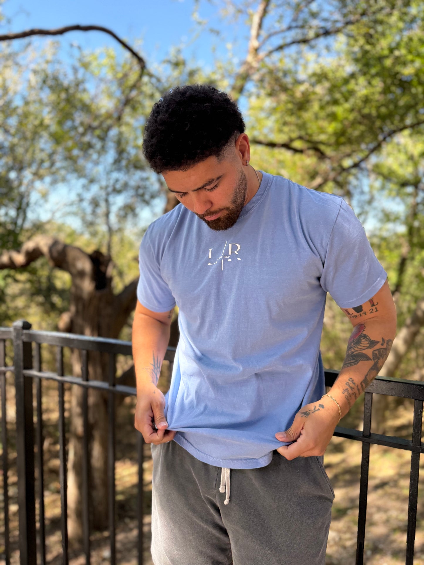 Man wearing a light blue t-shirt with a logo outdoors