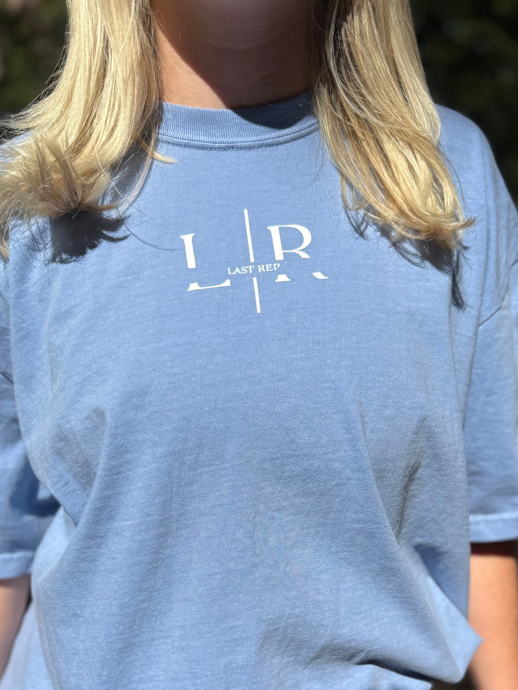 Person wearing a blue t-shirt with a logo, blurred face