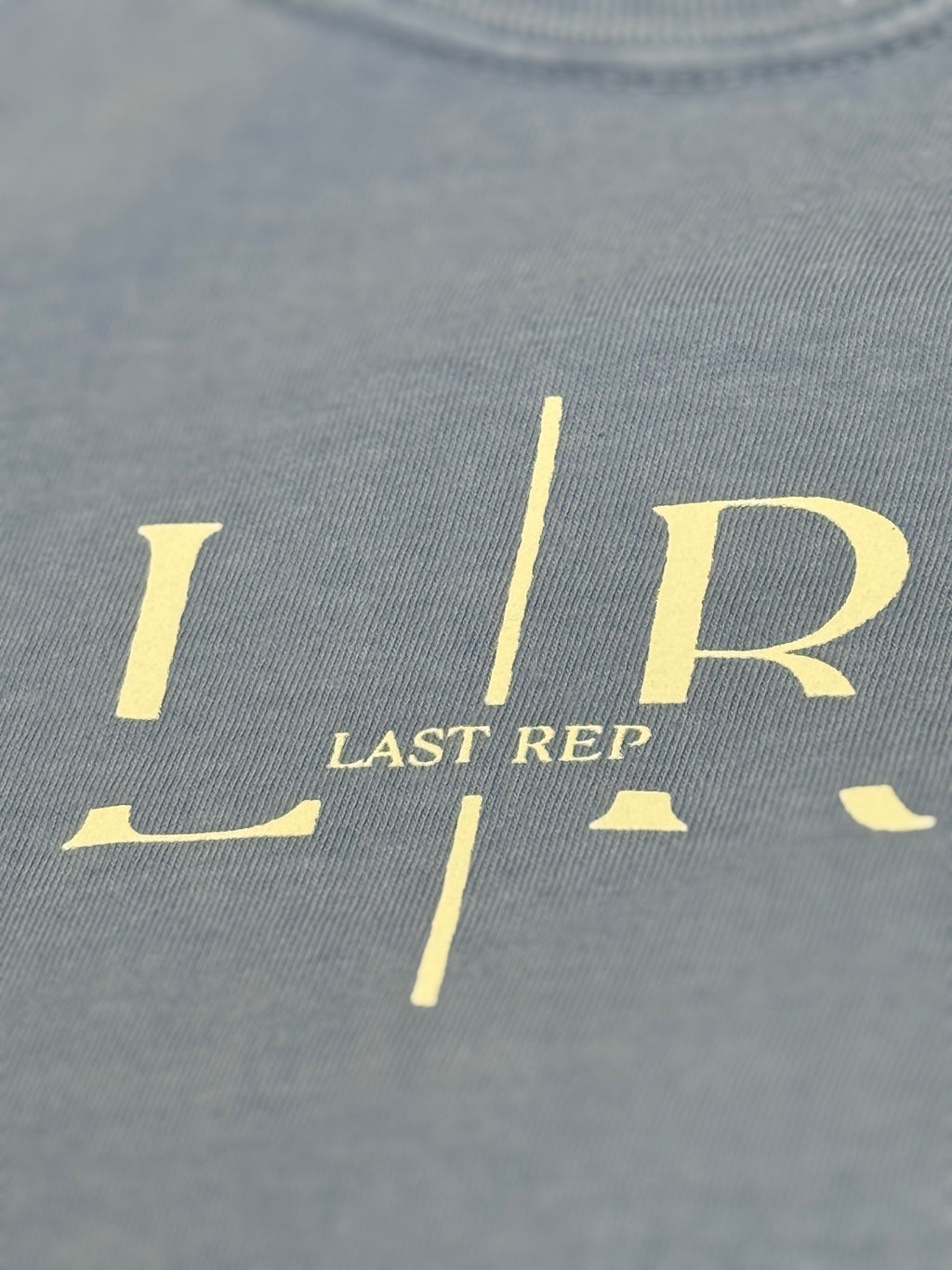 washed denim t-shirt with 'LR' logo and 'LAST REP' text in gold on a gray background