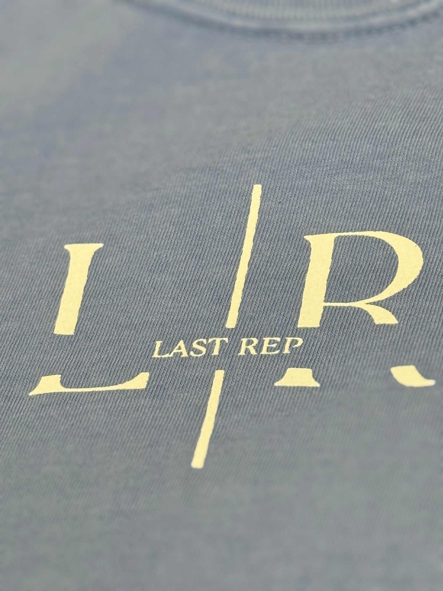 washed denim t-shirt with 'LR' logo and 'LAST REP' text in gold on a gray background