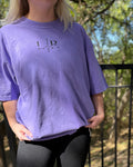 Person wearing a purple t-shirt with a logo outdoors