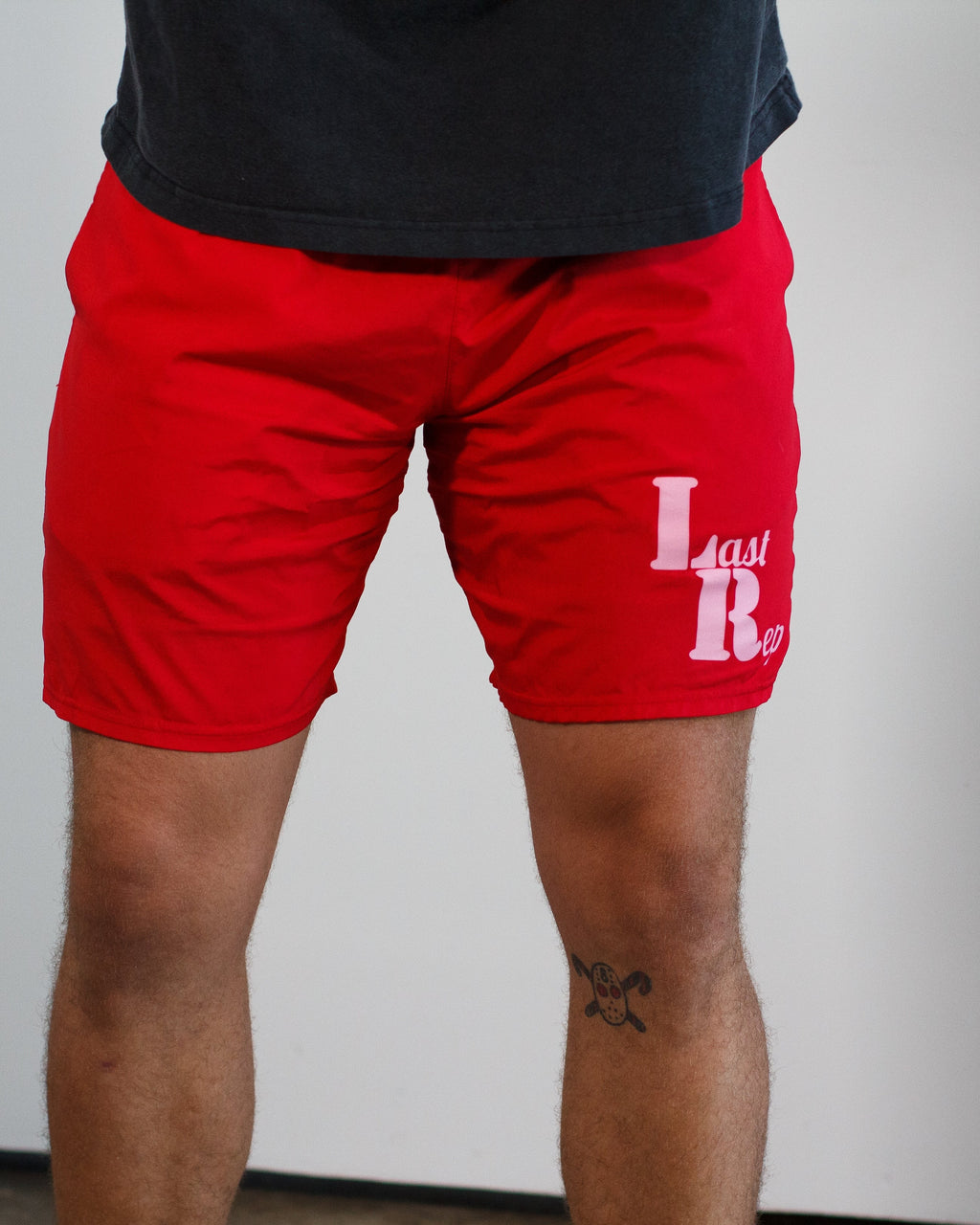 Red shorts with a Last Rep logo worn by a person on a plain background