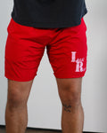 Red shorts with a Last Rep logo worn by a person on a plain background
