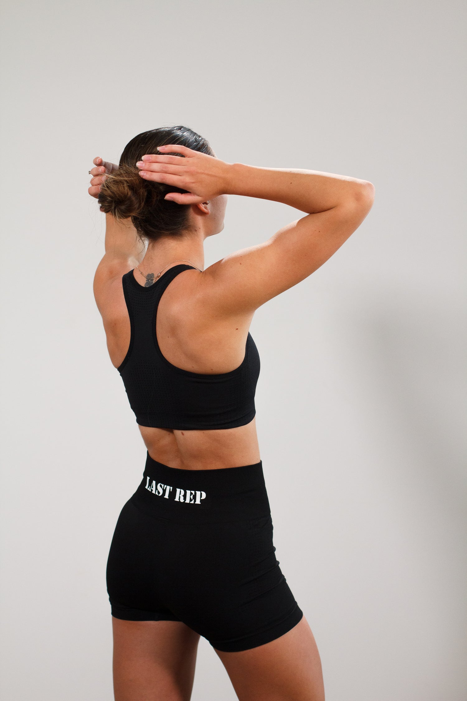 woman posing with black Last Rep sports bra and black Last Rep biker shorts