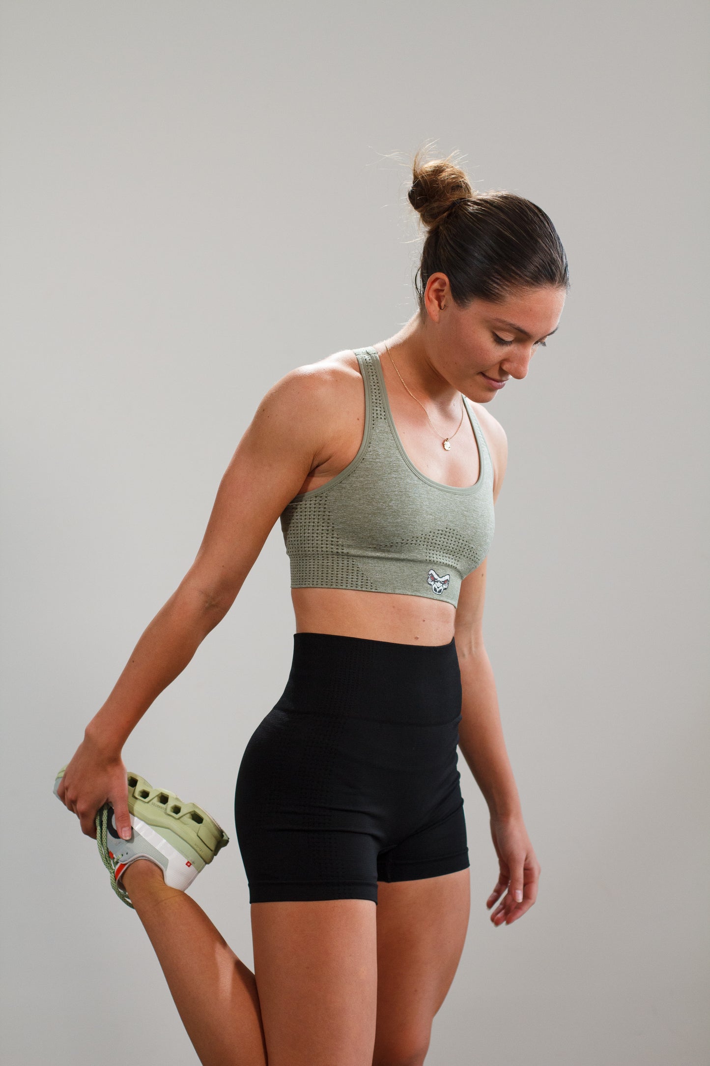 woman stretching with Last Rep green sports bra and Last Rep black biker shorts