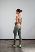 woman posing in studio with Last Rep green sports bra and leggings
