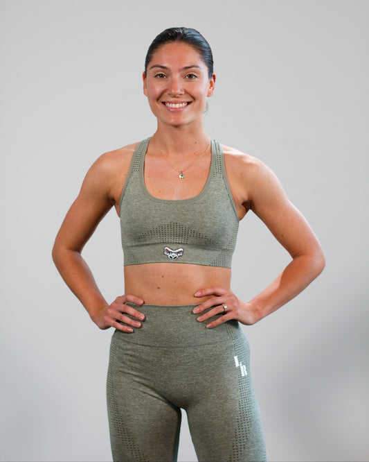 Woman wearing a Last Rep green sports bra and leggings set on a gray background