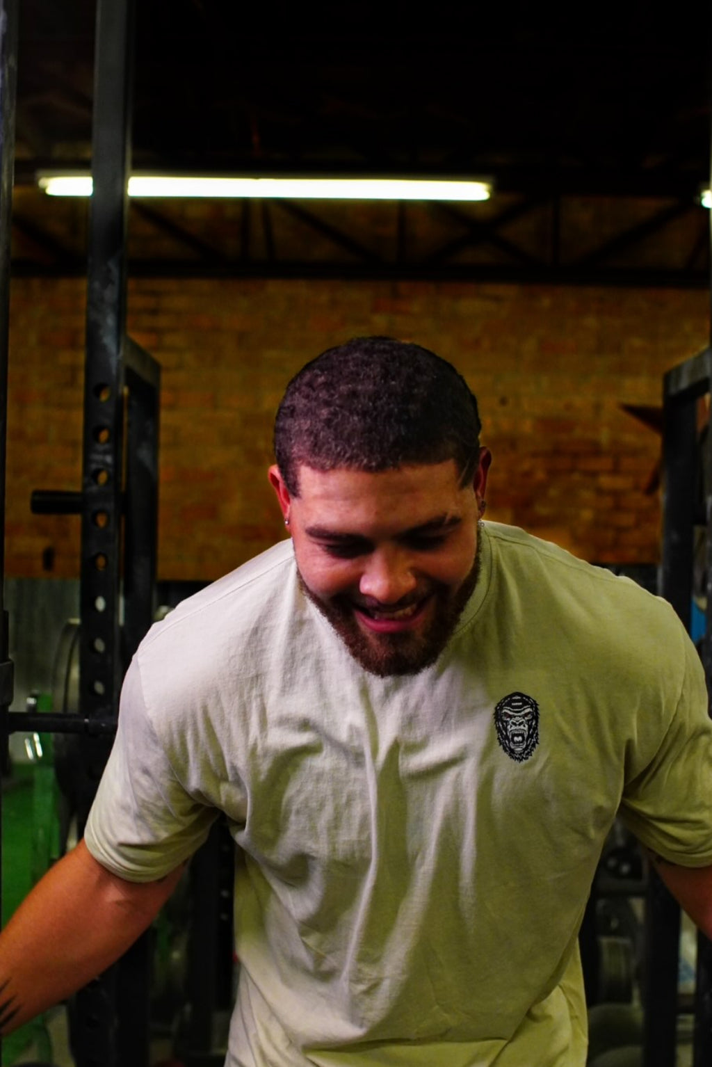 Men wearing oversized tan gym pump cover shirt with squat rack