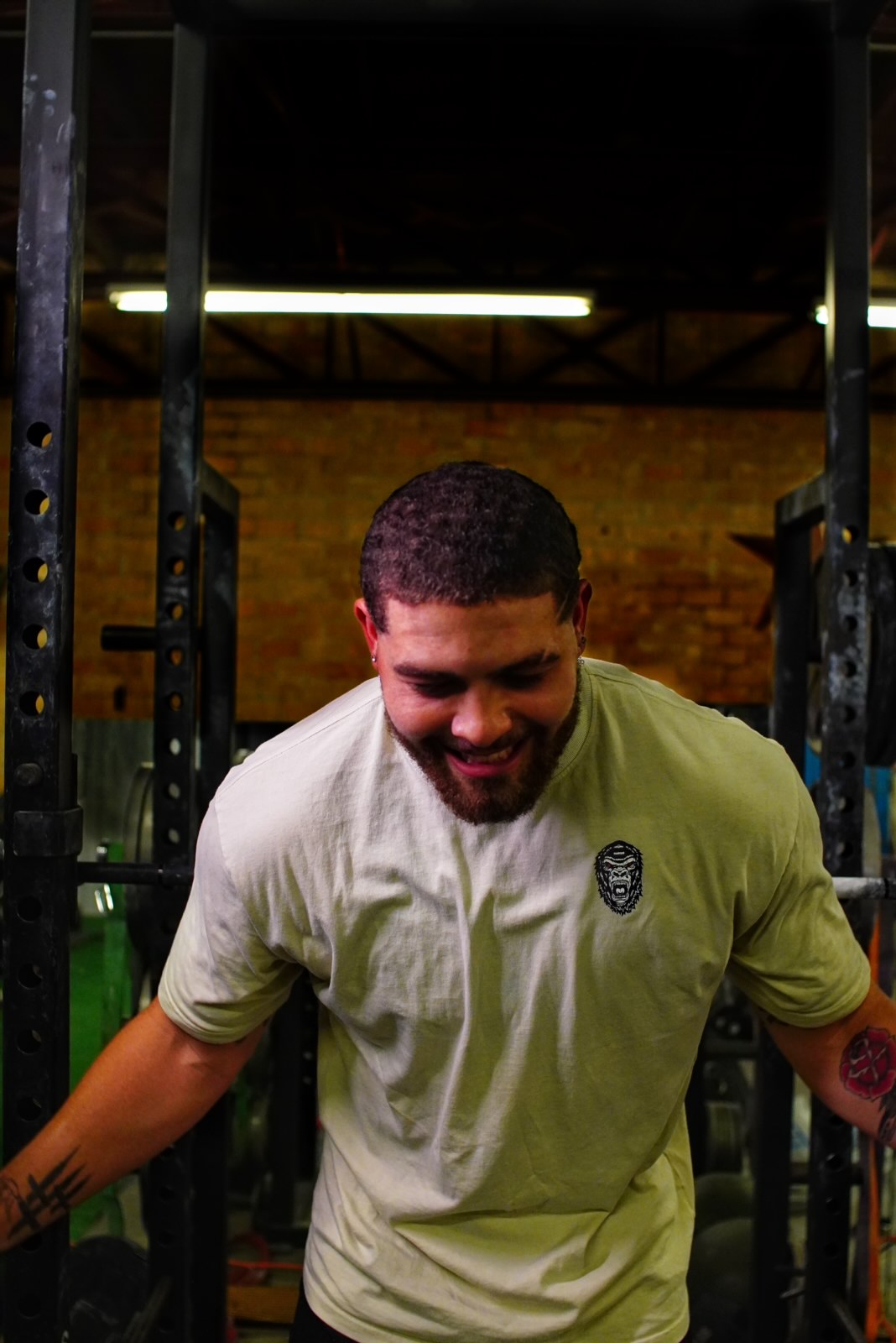 Men wearing oversized tan gym pump cover shirt with squat rack