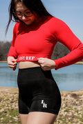 woman posing with red Last Rep long sleeve crop top and black Last Rep biker shorts