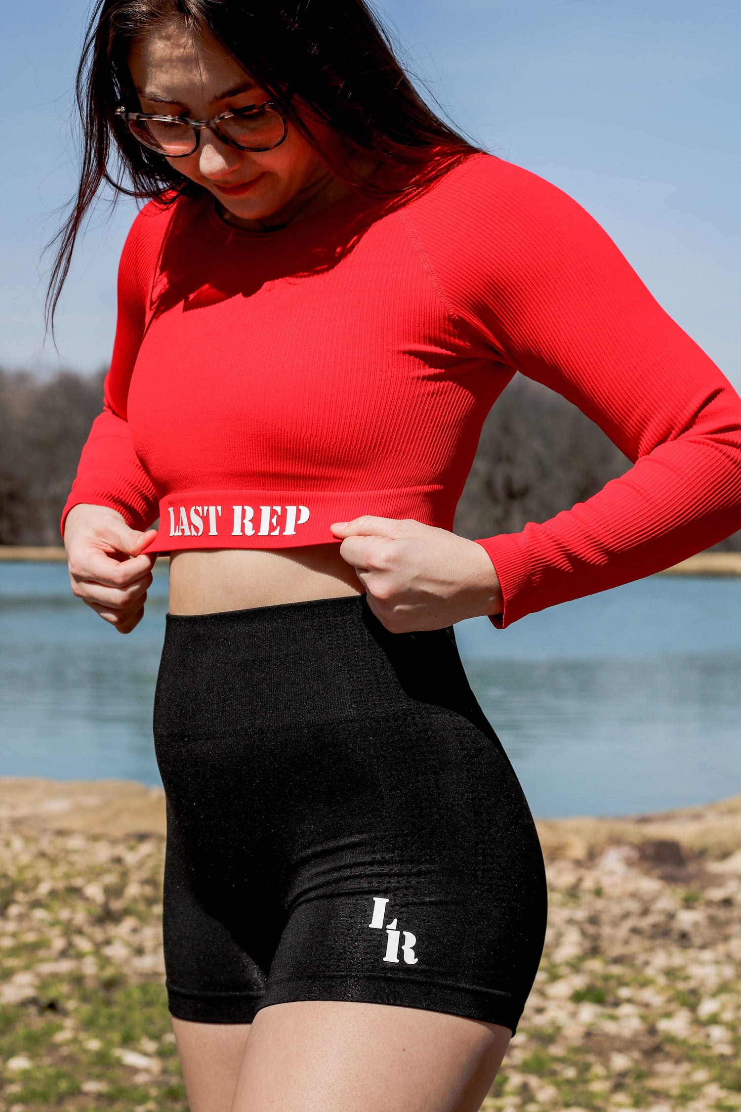 woman posing with red Last Rep long sleeve crop top and black Last Rep biker shorts
