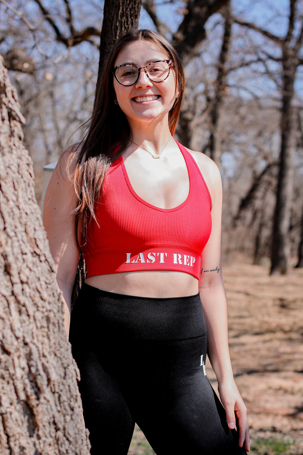 woman wearing Last Rep red bra and Last Rep black leggings