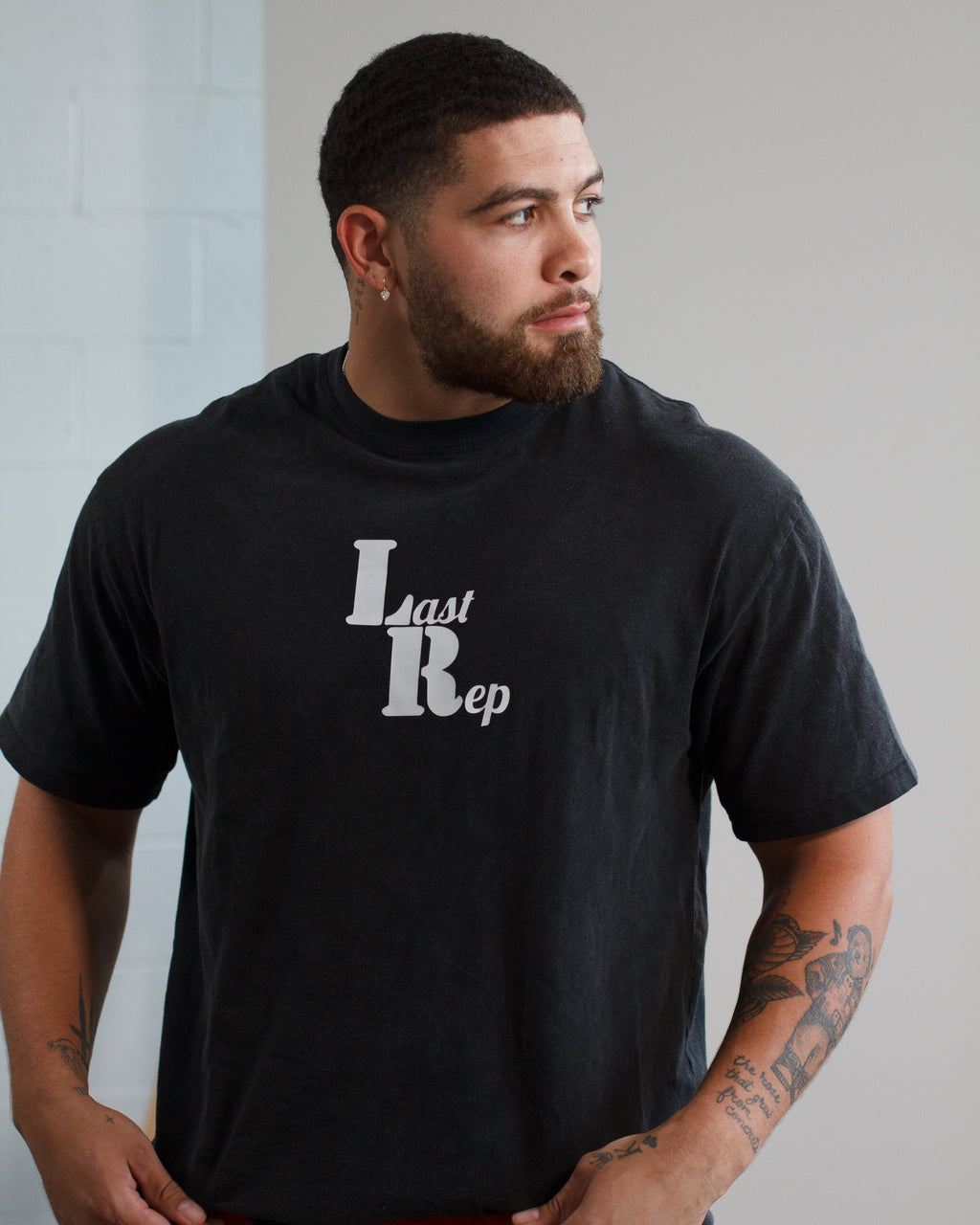 Man wearing a black t-shirt with 'Last Rep' logo against a plain background
