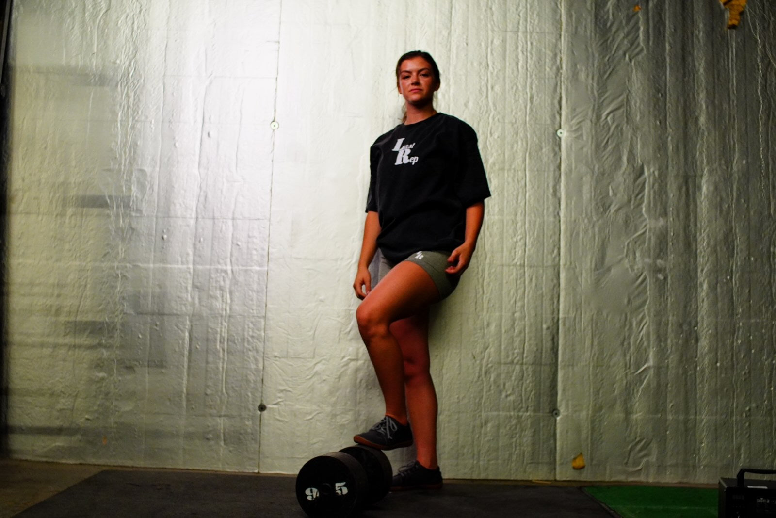 woman posing with black Last Rep pump cover and olive green Last Rep biker shorts