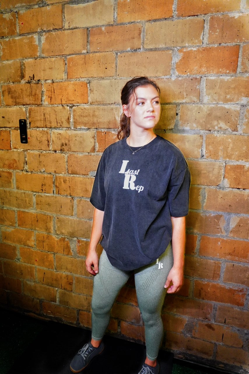 woman posing with black Last Rep cover and olive green Last Rep leggings