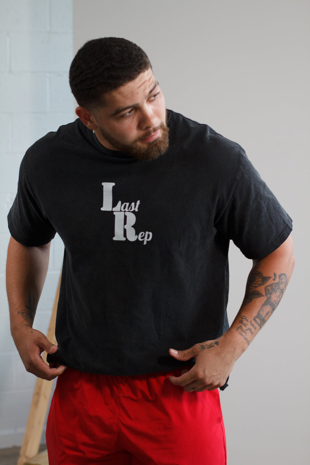 man posing with black Last Rep pump cover and red Last Rep shorts